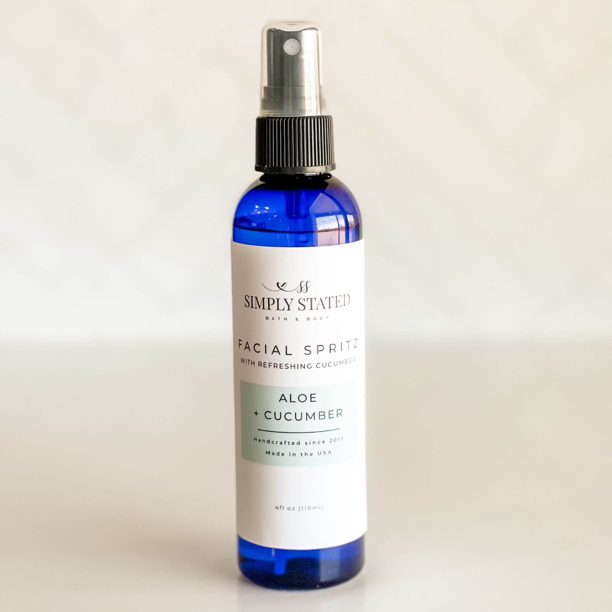 Close-up of Simply Stated Facial Spritz with Aloe + Cucumber, a hydrating mist in a sleek blue bottle, perfect for soothing and refreshing skin.