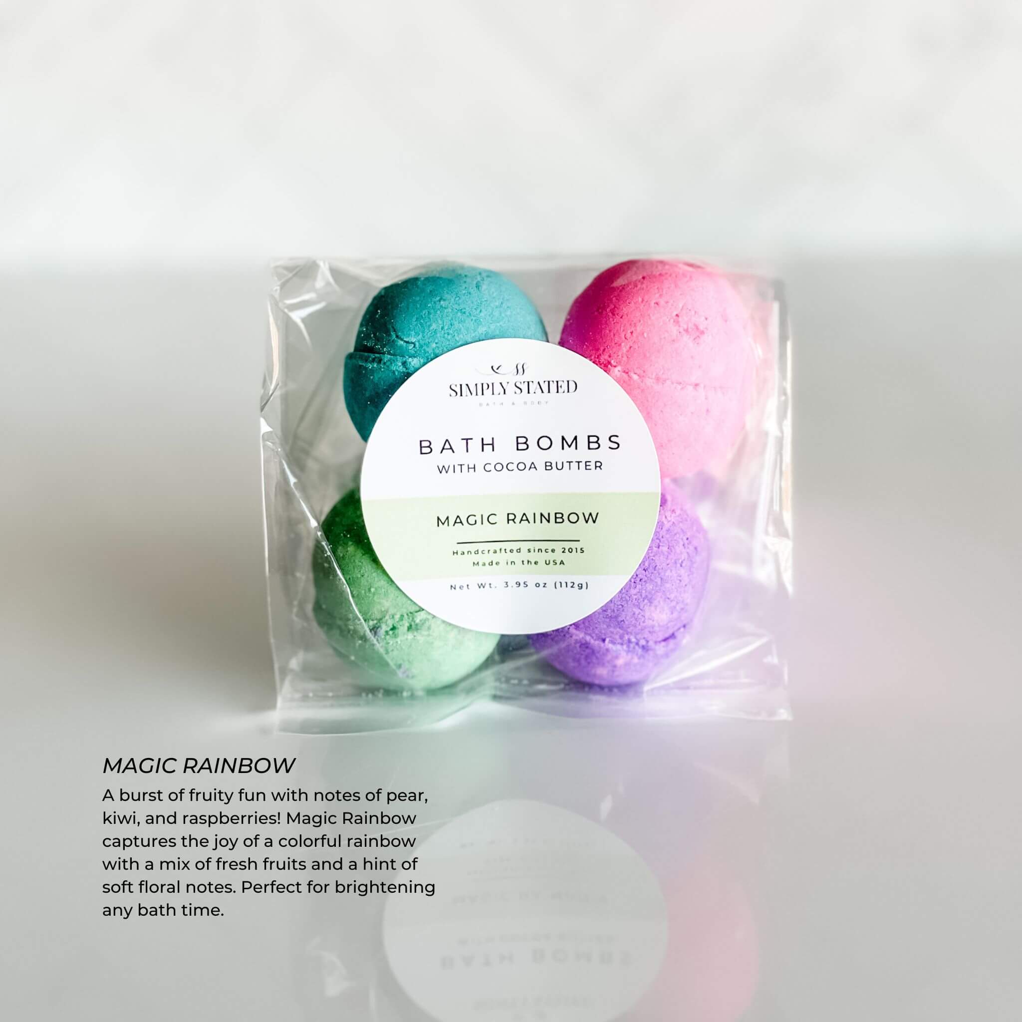 Simply Stated Kids Line Bath Bomb Pack in Magic Rainbow scent, featuring multicolored bath bombs in green, purple, pink, and blue, wrapped in clear packaging with a green-accented label.