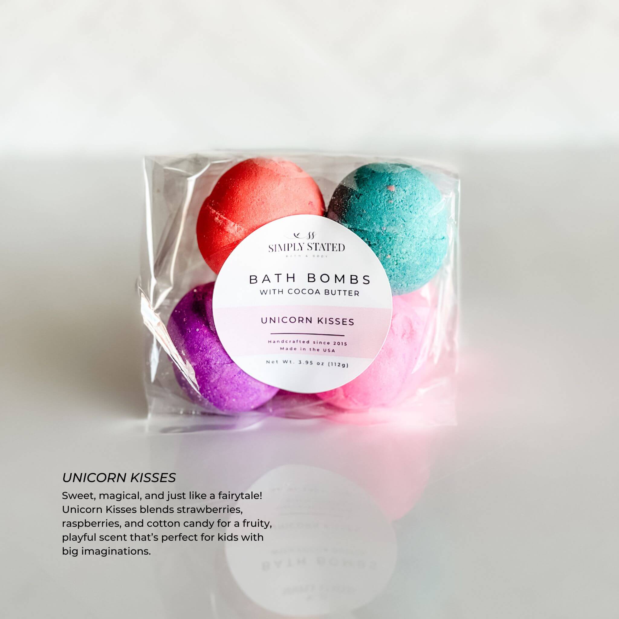 Simply Stated Kids Line Bath Bomb Pack in Unicorn Kisses scent, showing colorful pink, blue, and purple bath bombs, packaged with a pink-accented circular label.
