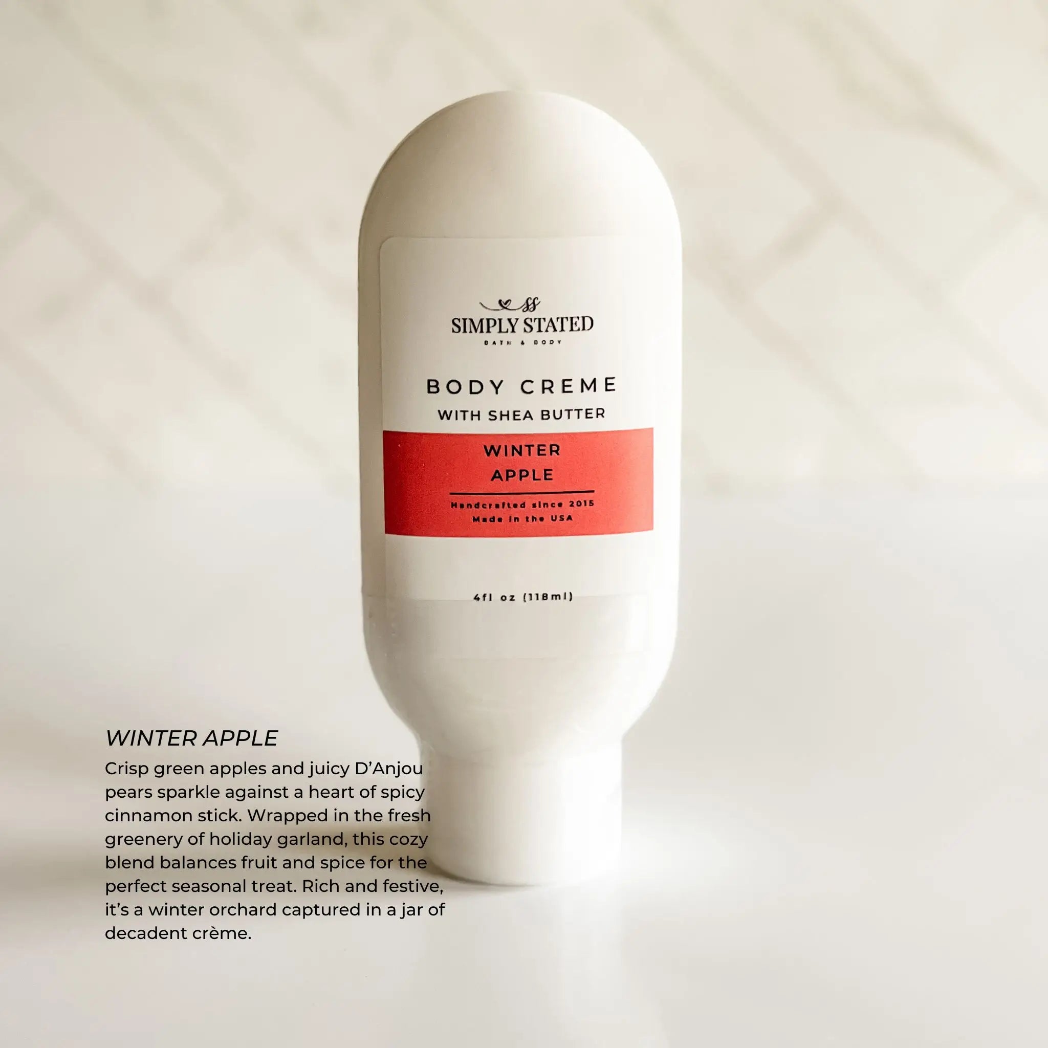 Body crème bottle labeled 'Simply Stated' with 'Winter Apple' flavor on a light background