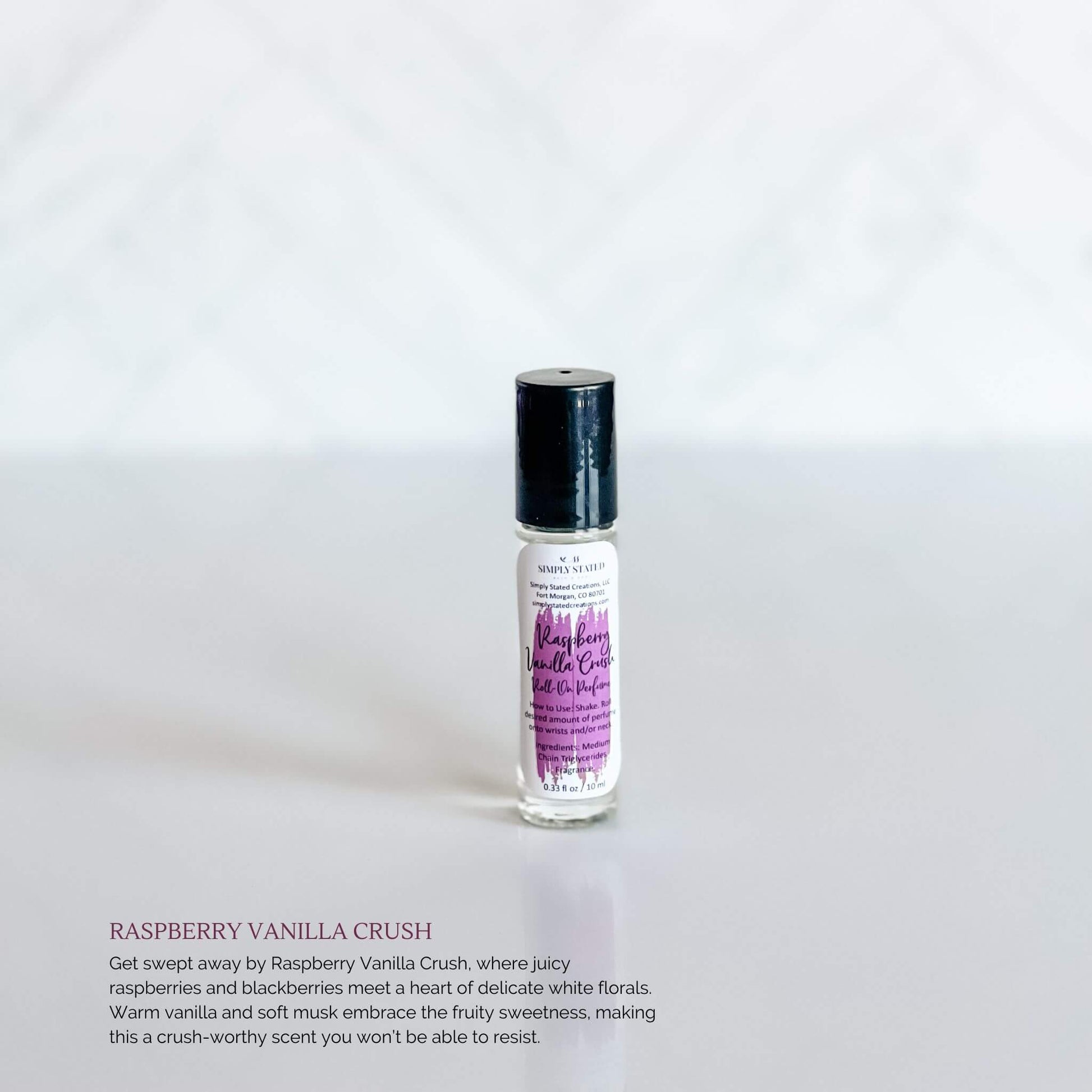 Simply Stated Bath & Body Raspberry Vanilla Crush Roll-On Perfume in a clear glass bottle with a purple label and black cap, displayed on a white background.