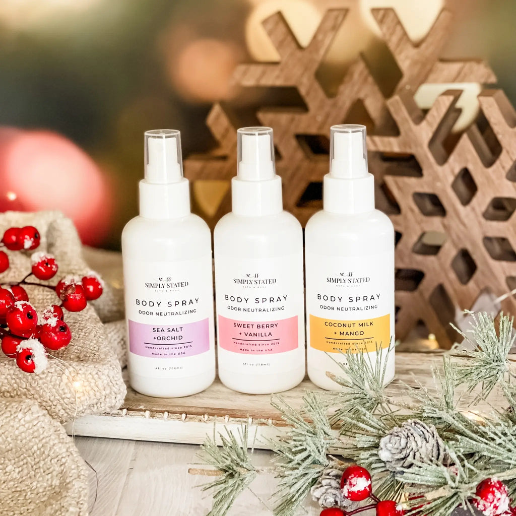 Three body spray bottles with different scents on a decorative background with Christmas elements.