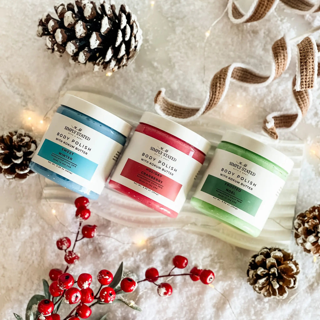 Three containers of body polish with decorative elements on a textured surface.