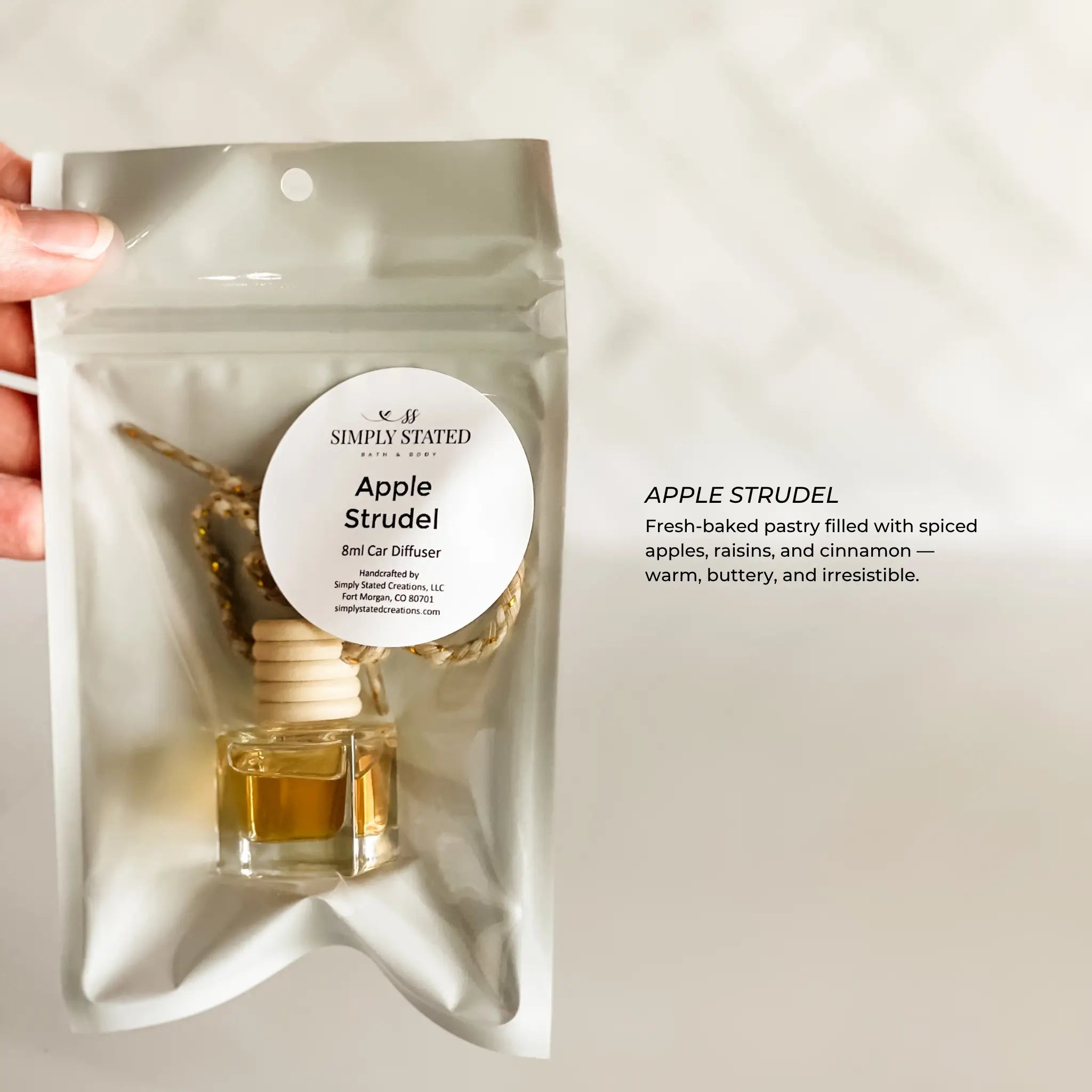 Car diffuser packaging labeled 'Apple Strudel' held by a hand on a light background